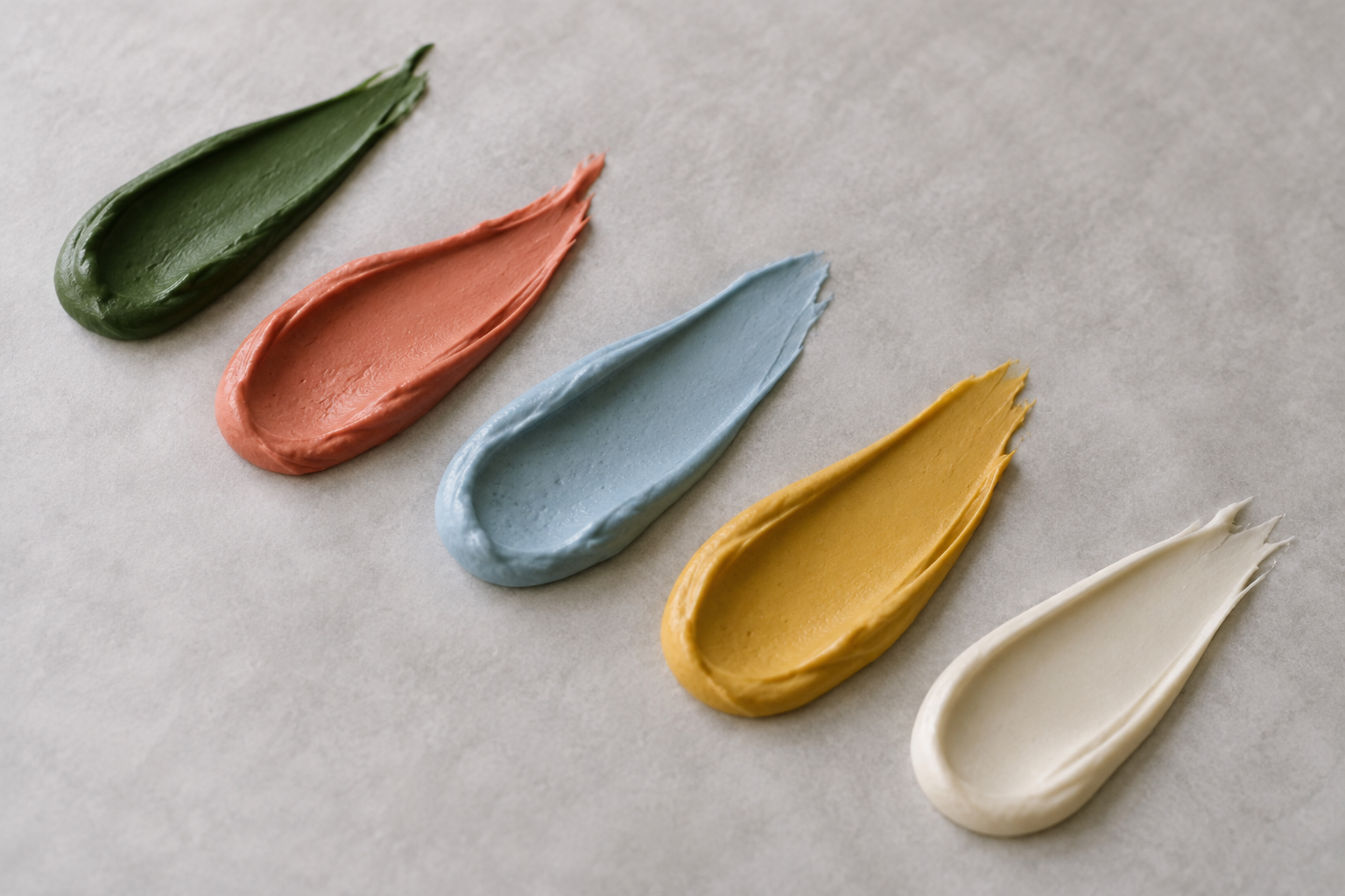 Five colorful royal icing swatches on parchment
